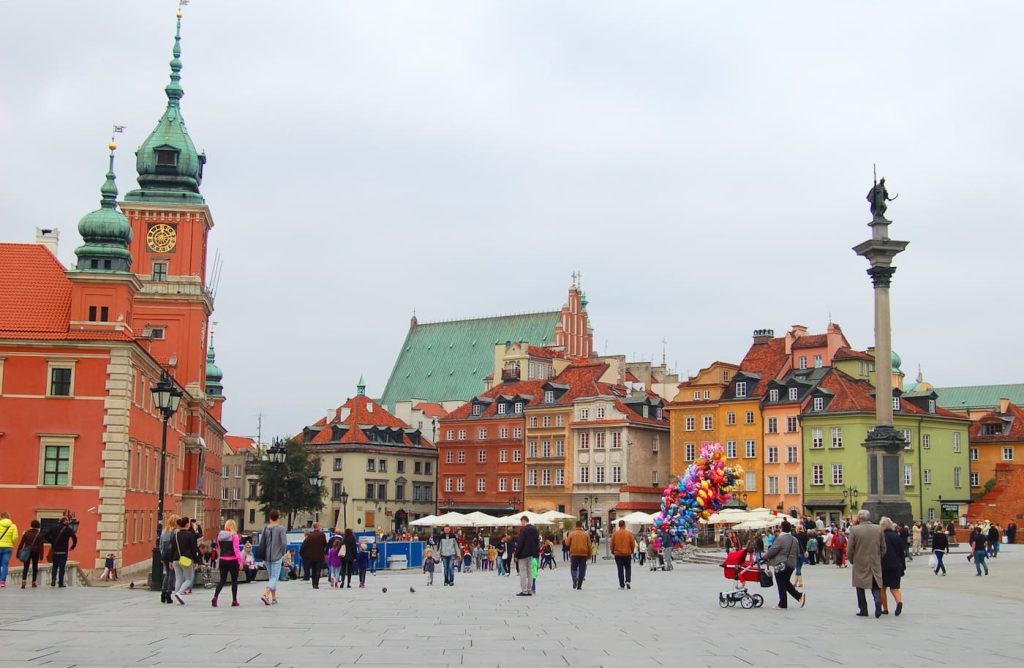 Tourists in Warsaw’s Old Town Square on a sunny day.