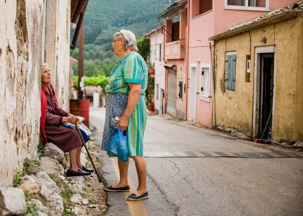 Two elderly women chatting on a quiet street in Doukades