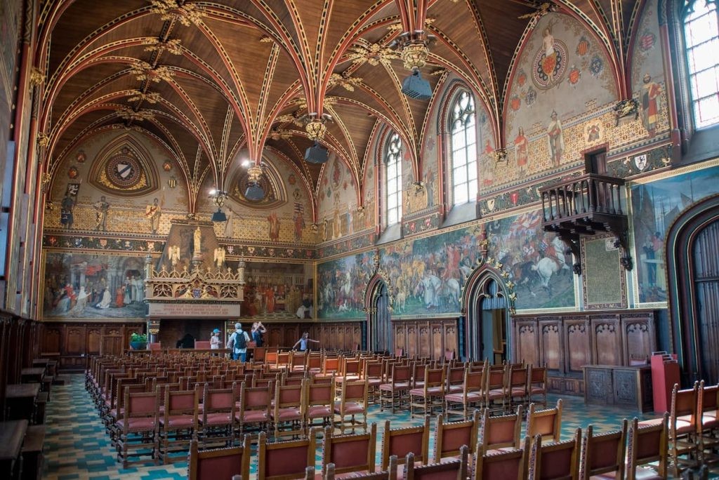 Ornate hall inside Bruges City Hall with wooden ceilings and murals