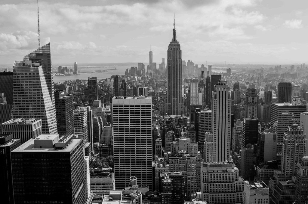 A black-and-white aerial view of New York City featuring the Empire State Building in the center.