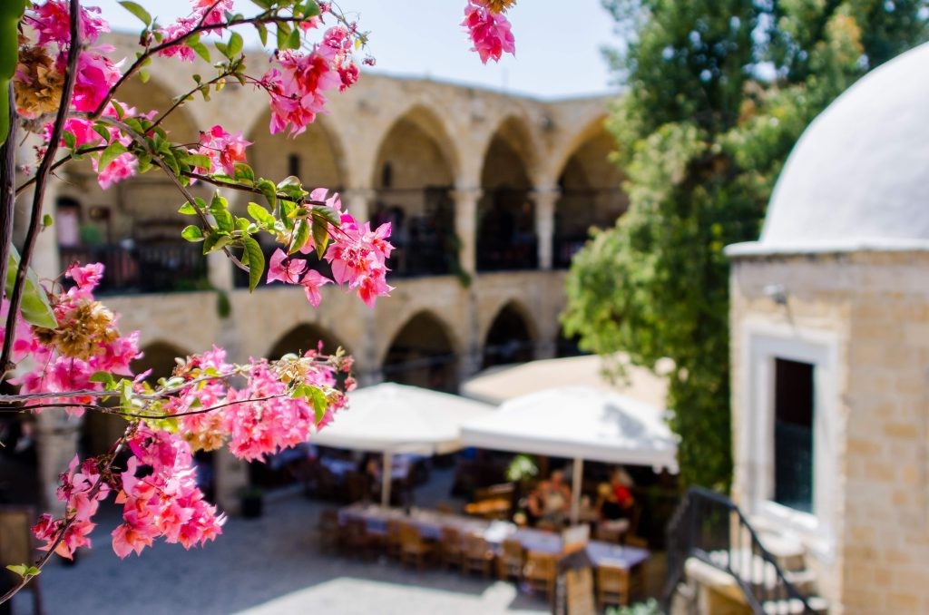 Historic courtyard at Büyük Han in Northern Cyprus with bougainvillea and arches.