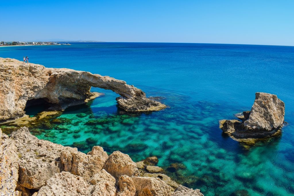 Natural stone arch over calm, turquoise water near Cape Greco, Cyprus.
