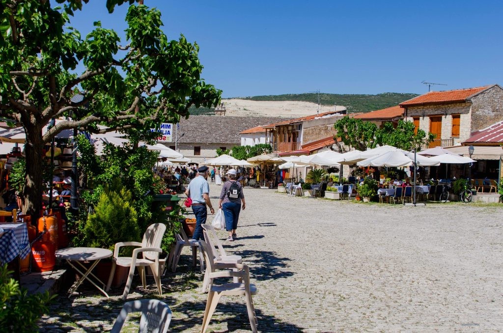 Wide stone street lined with cafés and shops in Omodos village, Cyprus.