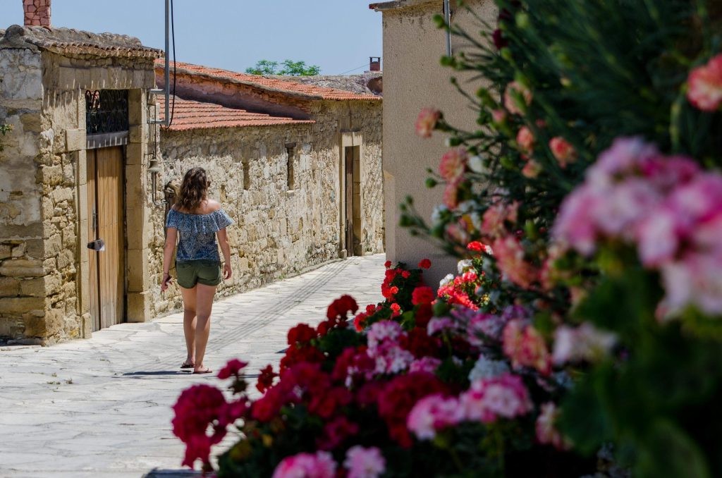 Traveller walking down a flower-lined stone street in Cyprus.