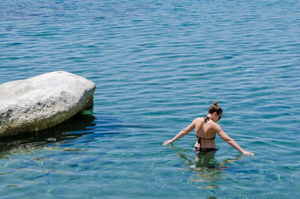 Traveller standing waist deep in the calm, blue sea in Cyprus.