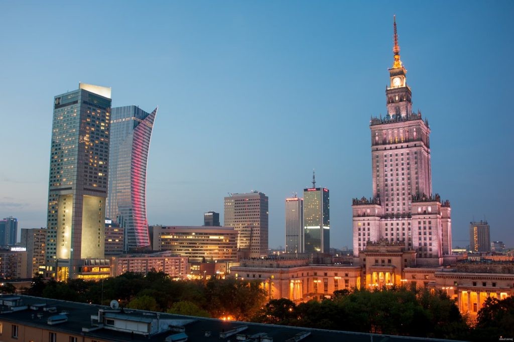 Warsaw skyline at dusk with modern skyscrapers illuminated.