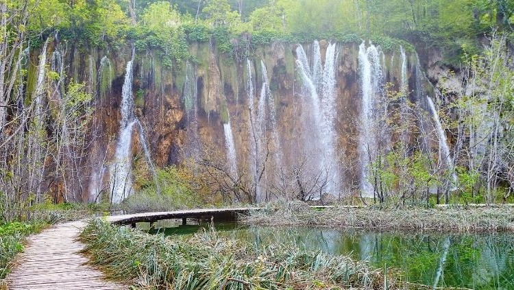 Boardwalk over turquoise water and waterfalls at Plitvice Lakes