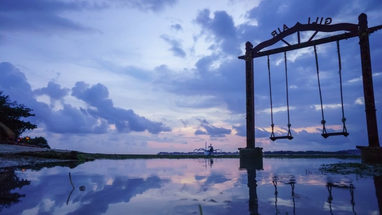 Swings over the water at twilight in Gili Air